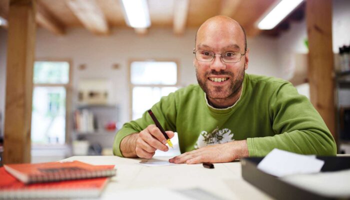 Mann schaut in Kamera mit Stift